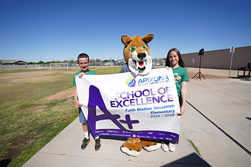 Two students outside holding banner with school mascot